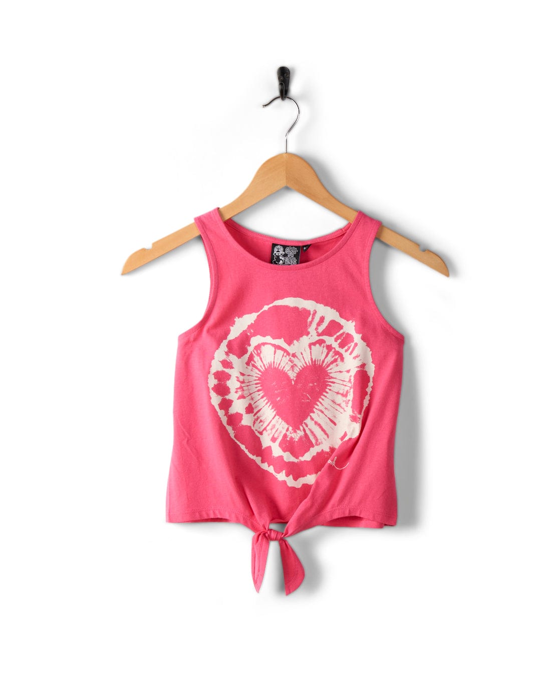 A Saltrock Tie Dye Heart - Kids Tie Front Vest - Pink made of soft cotton, featuring a heart-shaped tie-dye pattern on the front, hanging elegantly on a wooden hanger with a bottom tie detail.