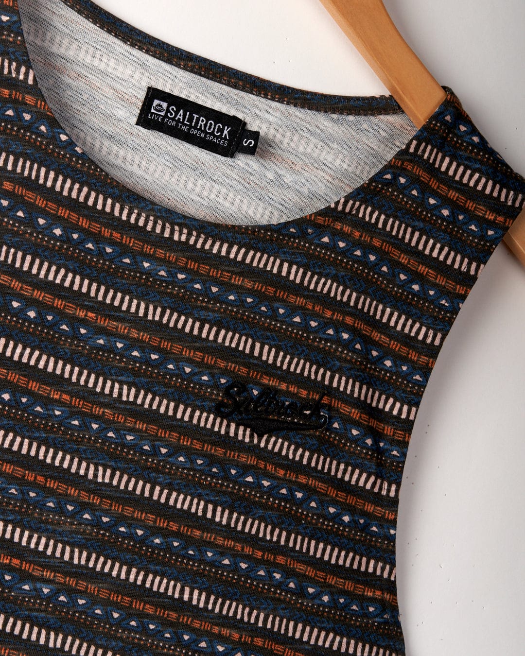 Close-up of a sleeveless top with a blue and orange geometric pattern, displayed on a wooden hanger. The label reads "Saltrock Live For The Open Spaces" with the size "S". Featuring Saltrock branded embroidery, this piece is crafted from 100% cotton for comfort and style.