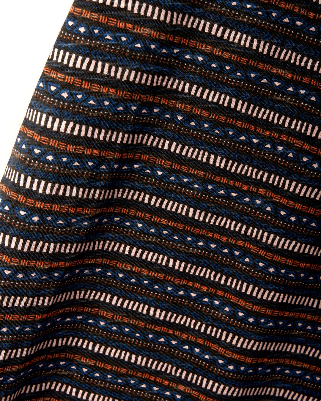 Close-up of fabric with a tribal stripe pattern featuring geometric shapes in blue, orange, and black. The texture highlights the Saltrock branded embroidery on the 100% cotton material of the Tribal Stripe - Womens Midi Dress - Grey.