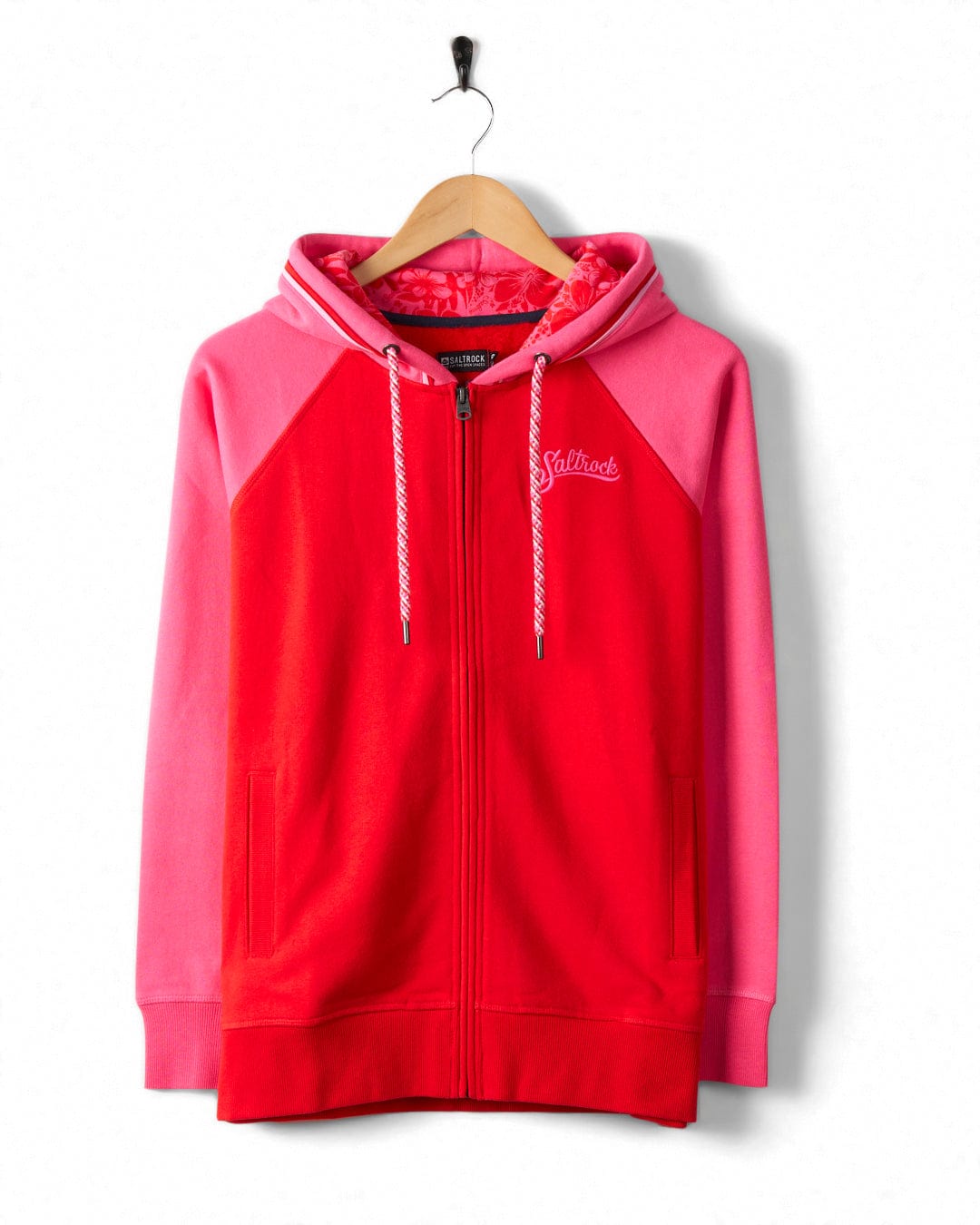 A Tropic - Womens Zip Hoodie - Red with a white Saltrock branding embroidered on the chest and white drawstrings, hanging from a black hook.