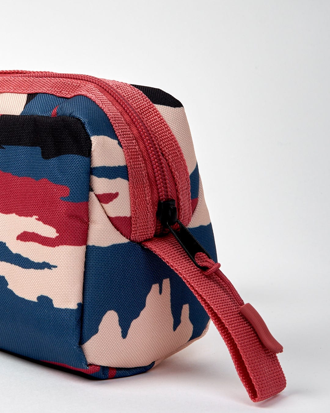 Close-up of the Saltrock Uni Mountain Scape pencil case with a colorful camouflage pattern in red, blue, beige, and black. The polyester pencil case features a large compartment, with the zipper and pull tab in striking red.