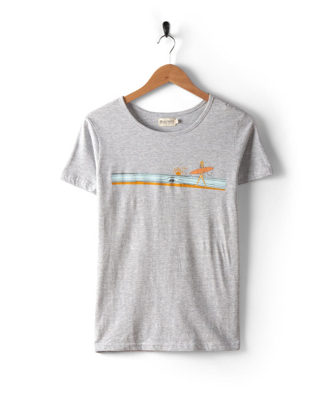 The Waveline Women's T-Shirt in grey by Saltrock is displayed on a wooden hanger against a white background. It features a small graphic of surfers and waves, is made from 100% cotton, includes distinctive Saltrock graphics, and is machine washable for easy care.