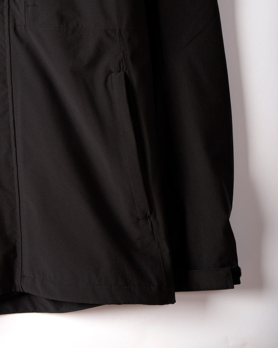 Close-up of the lower half of the Whistler II, a black waterproof jacket from Saltrock, showcasing a visible pocket and sleeve against a white background.