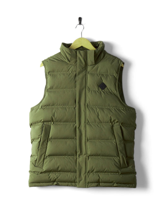 A Saltrock Xavier men's padded gilet in green, featuring a high collar and detachable hood, made from water-resistant polyester, is hanging on a wooden hanger against a white wall.